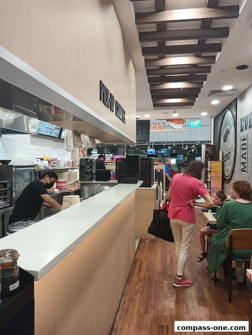 Interior view of a sushi restaurant with a pick-up counter and customers dining.