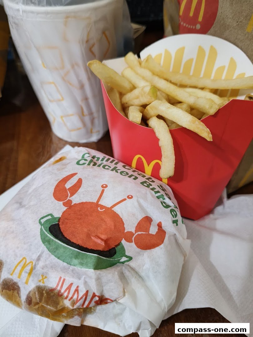 A McDonald's Chilli Crab Burger and fries are displayed with drinks.