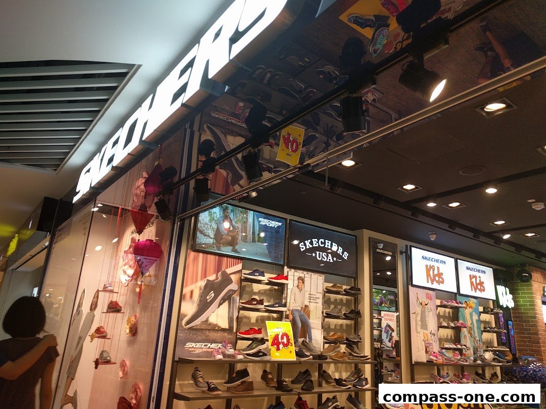 The Skechers store front displays shoes and promotional signage, with a customer looking at the display.