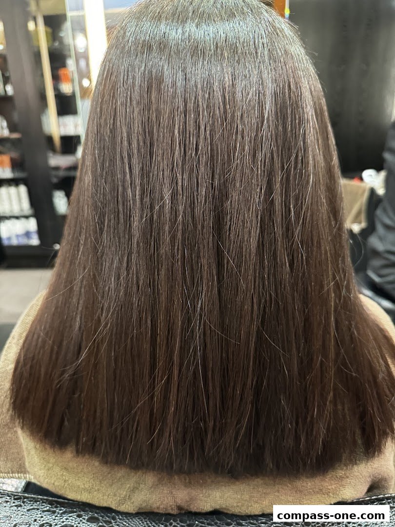 A person's back with freshly styled, long, dark brown hair.