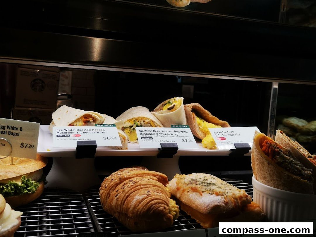 A display case filled with various breakfast wraps, sandwiches, and pastries at Starbucks.