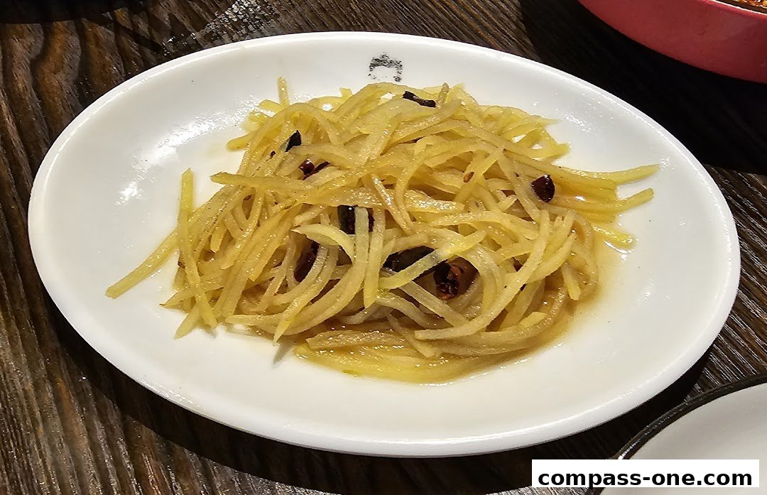 A close-up shot of a white plate filled with shredded potatoes and chili peppers.
