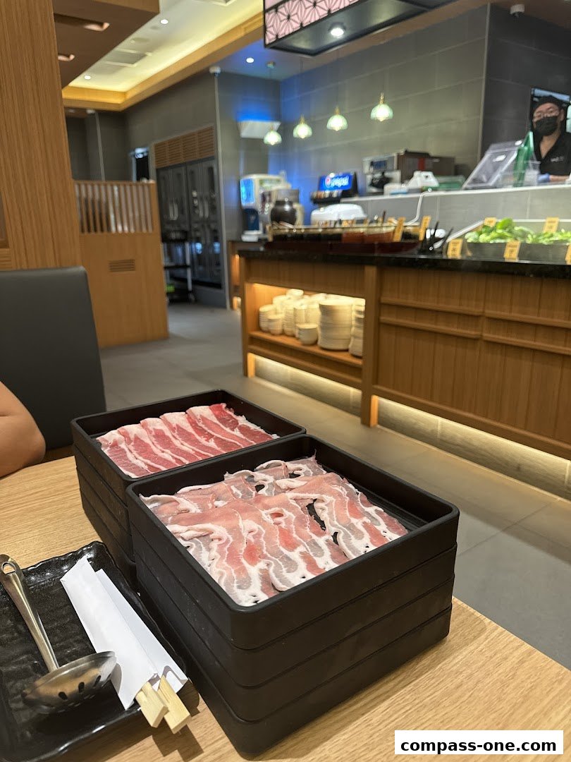 Two trays of thinly sliced raw meat, likely for hot pot or shabu-shabu, are displayed on a table.