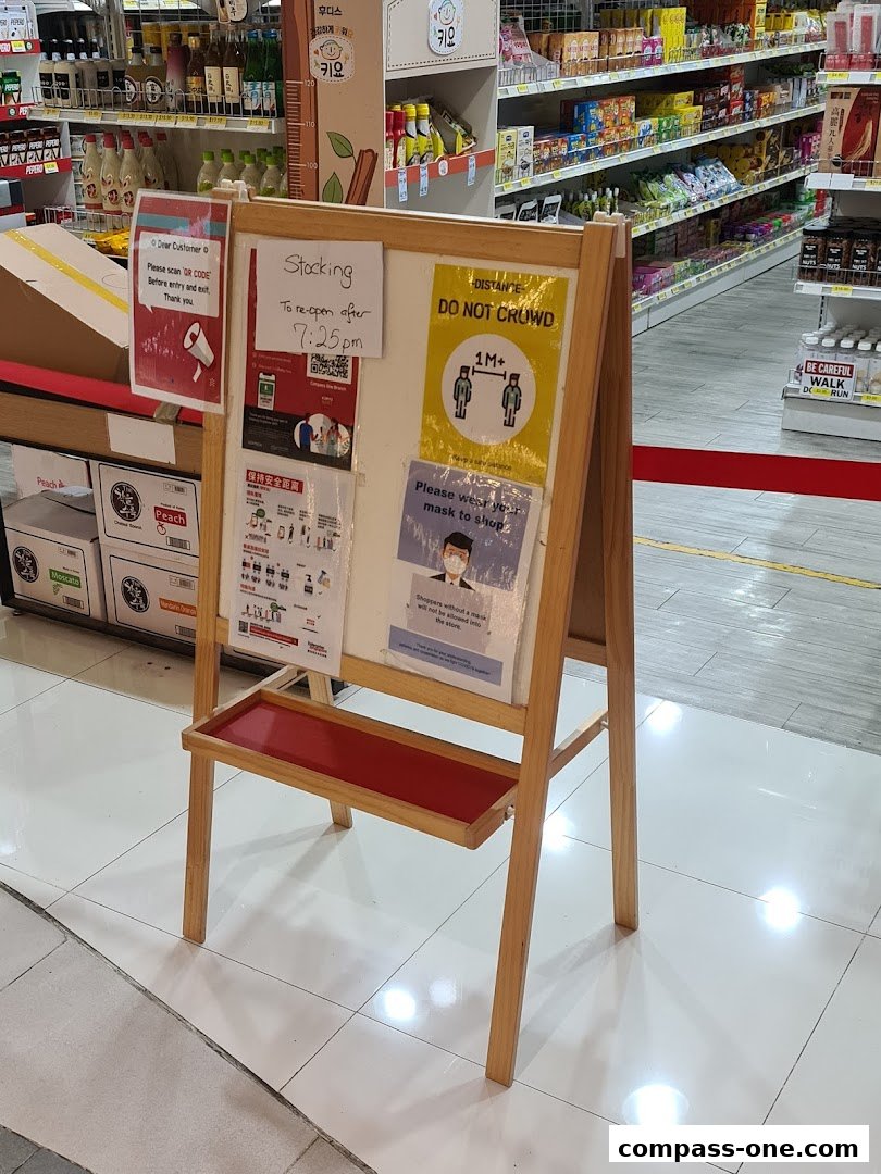 A wooden easel displays various notices including social distancing and mask-wearing guidelines.