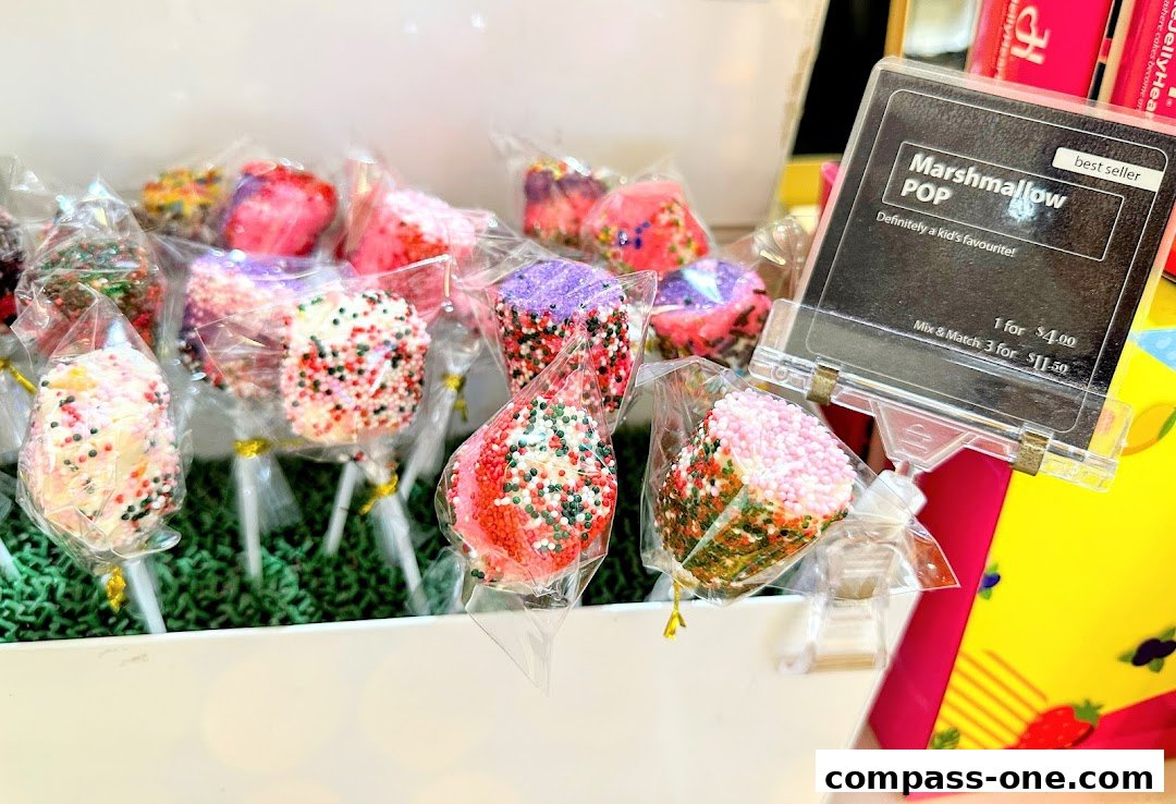 A display of colorful marshmallow pops covered in sprinkles, with a price sign.