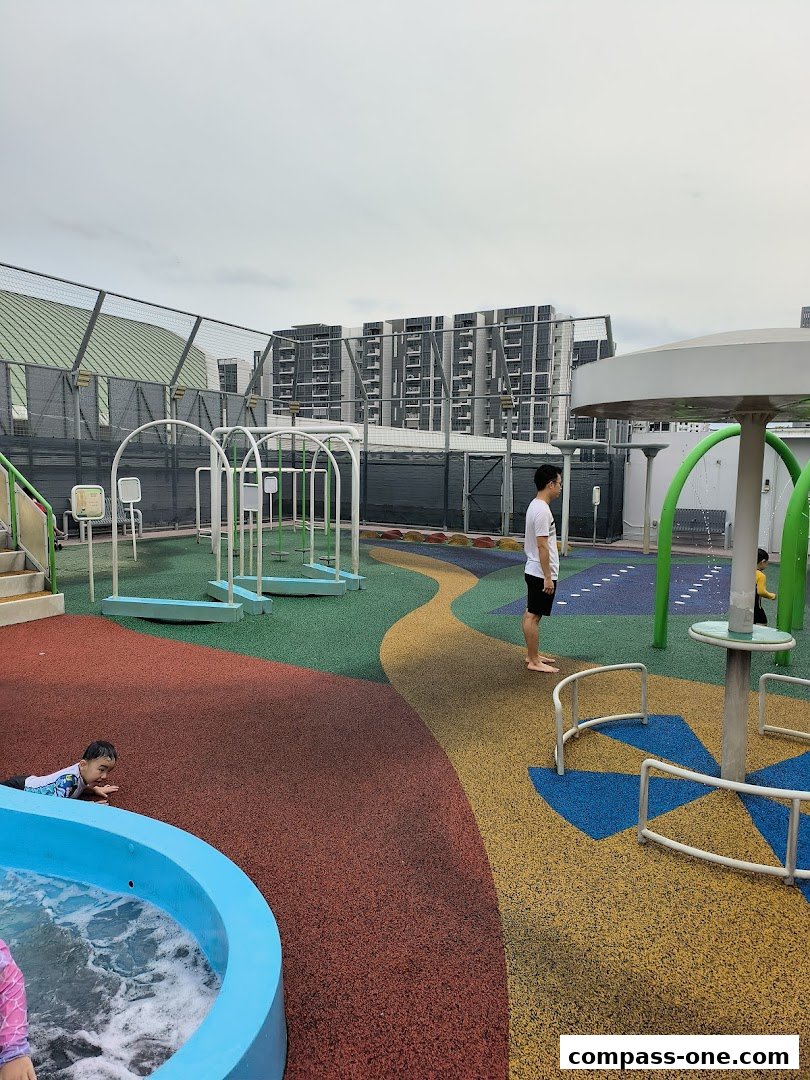 A colorful outdoor water playground with children and adults enjoying the facilities.