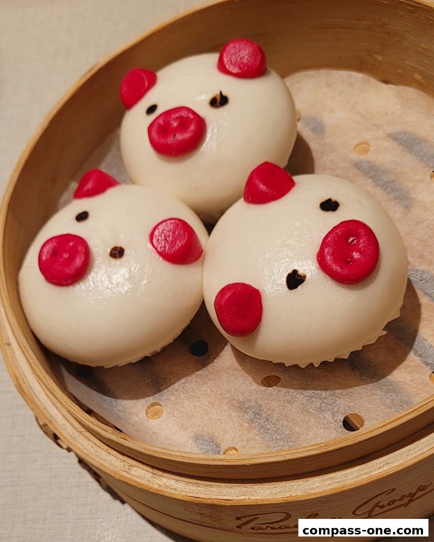 Three adorable steamed buns shaped like pigs in a bamboo steamer.
