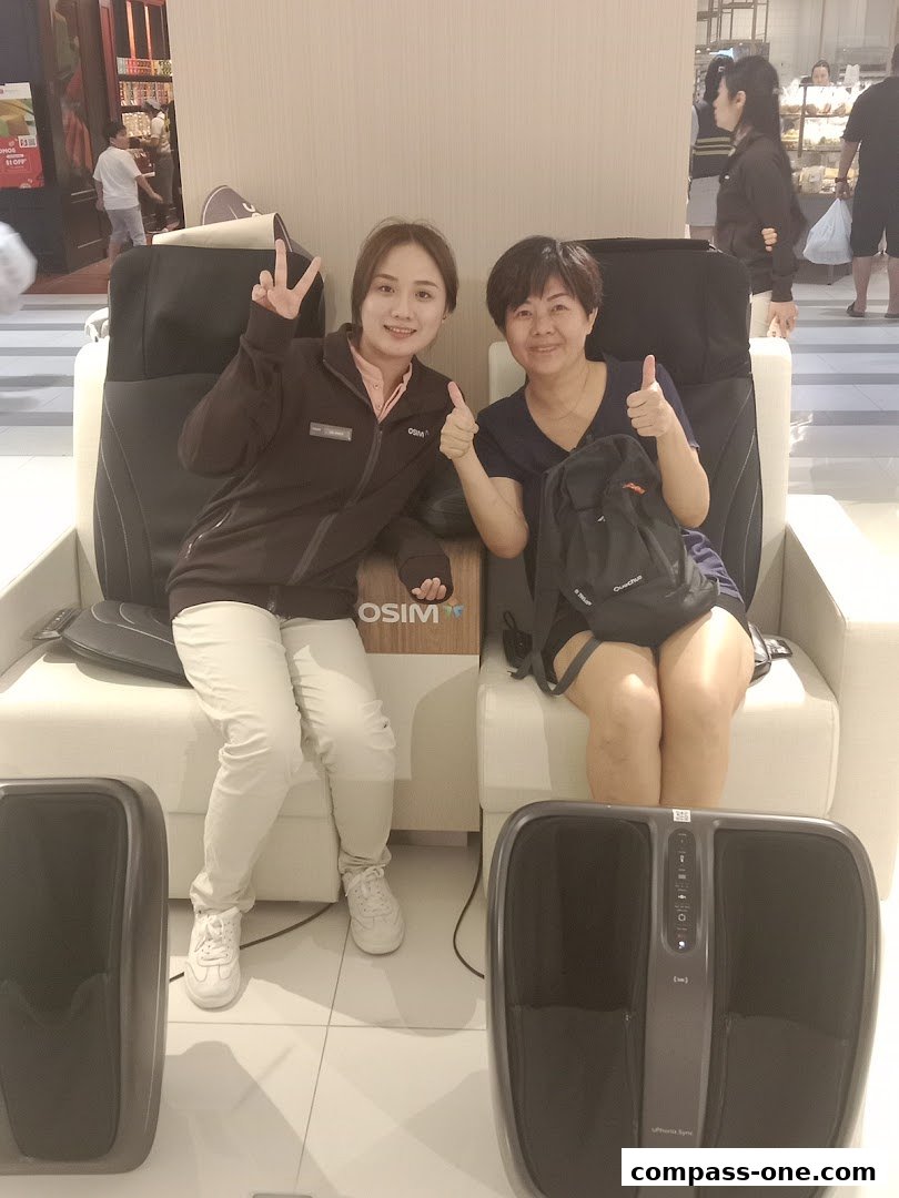 Two women are sitting in OSIM massage chairs, smiling and giving thumbs up.