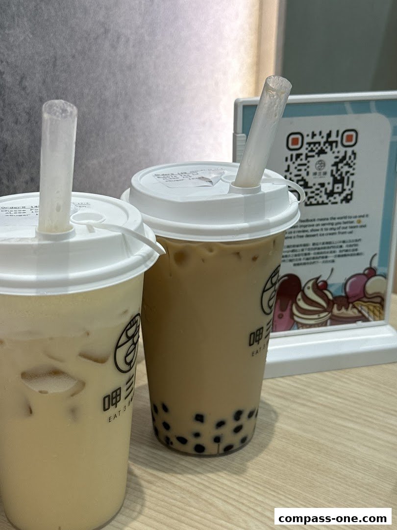 Two bubble tea drinks with boba pearls and straws on a wooden table.