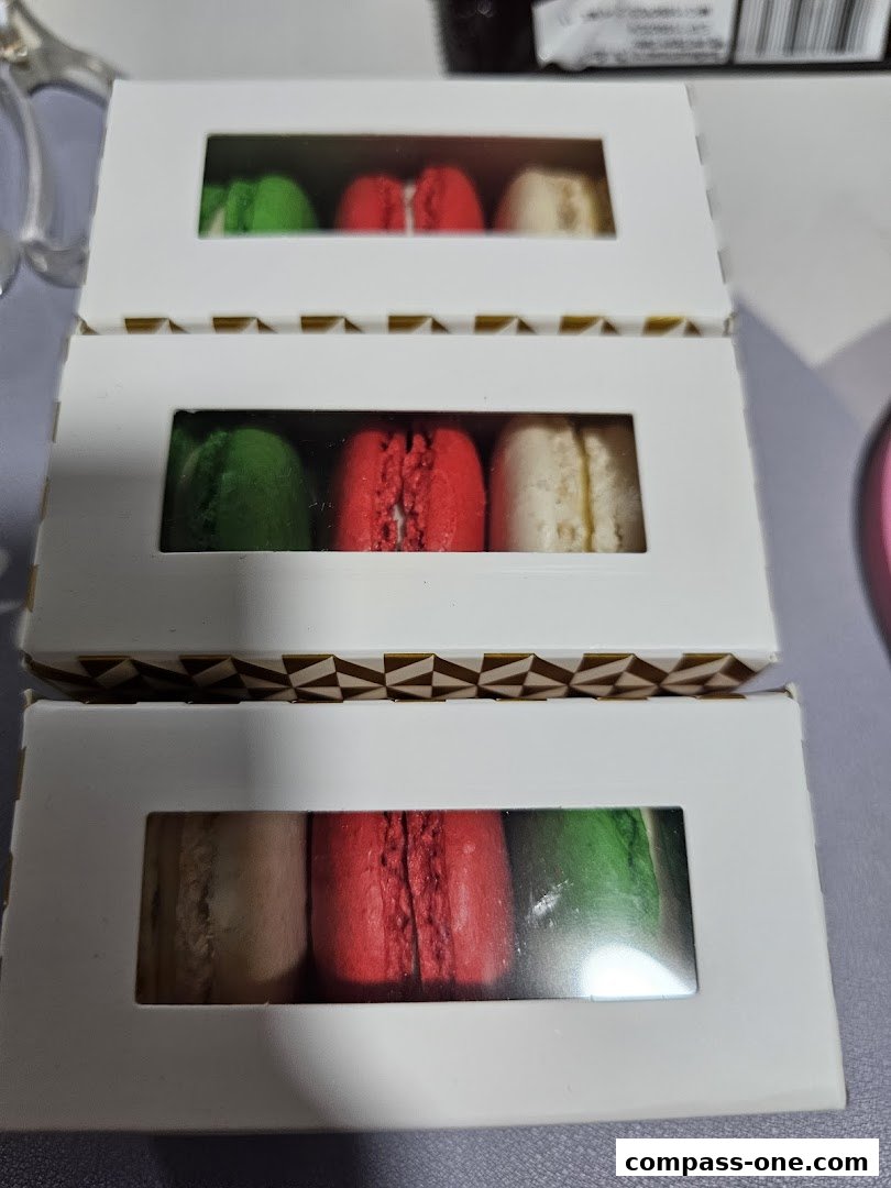 Three white boxes with windows, each containing colorful macarons.
