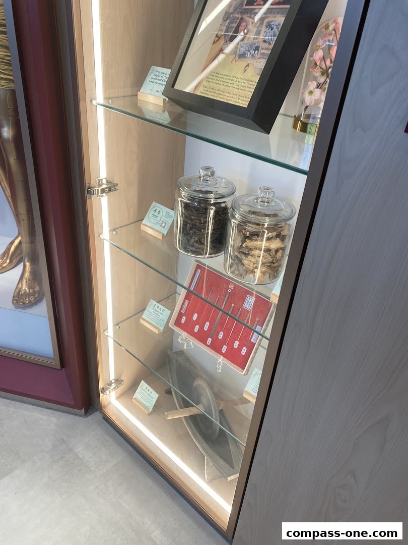A display cabinet showcasing traditional Chinese medicine herbs, tools, and historical photos.