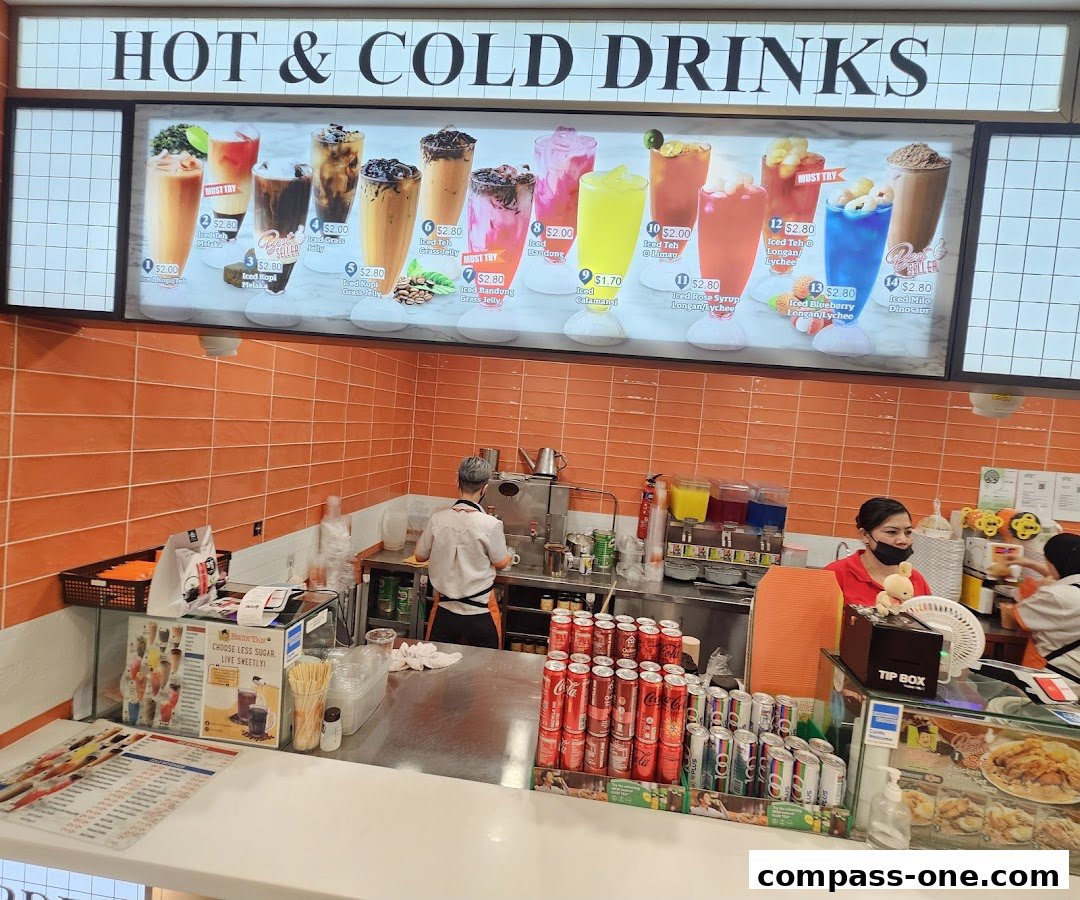 A counter at Encik Tan with a hot and cold drinks menu board and staff preparing drinks.