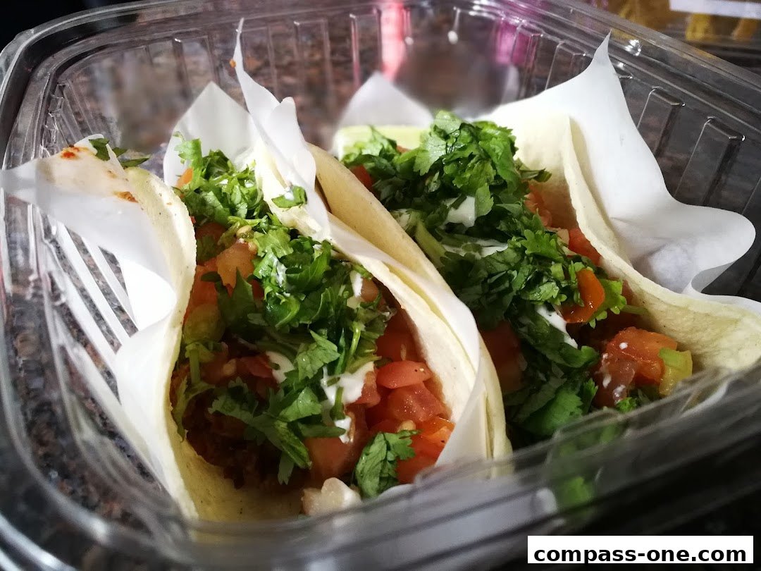 Two delicious tacos filled with fresh ingredients, served in a clear plastic container.