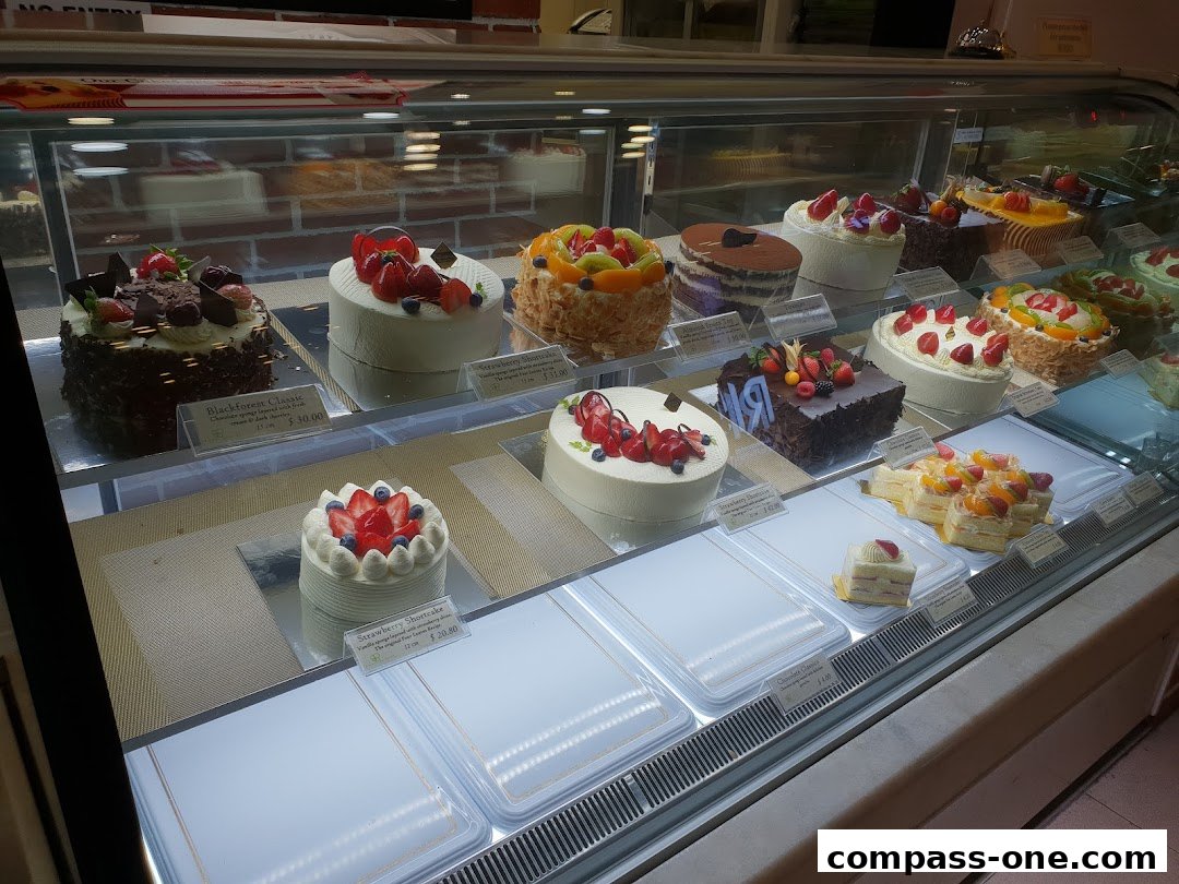 A display case filled with a variety of beautifully decorated cakes and pastries.