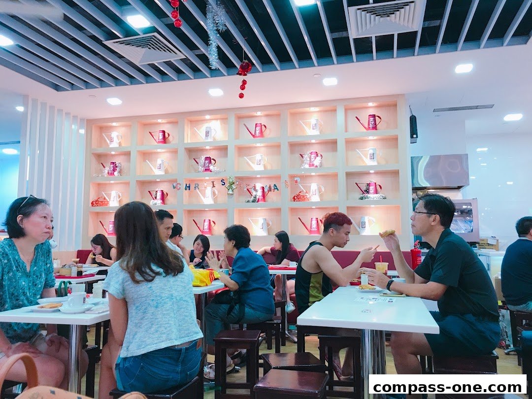 Diners enjoy meals at Ya Kun Kaya Toast, with a decorative wall featuring watering cans.