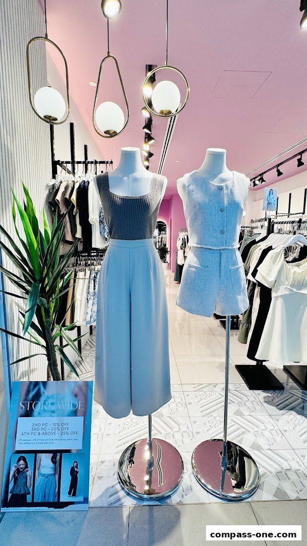 Mannequins display stylish outfits in a bright, modern clothing store with sale signage.