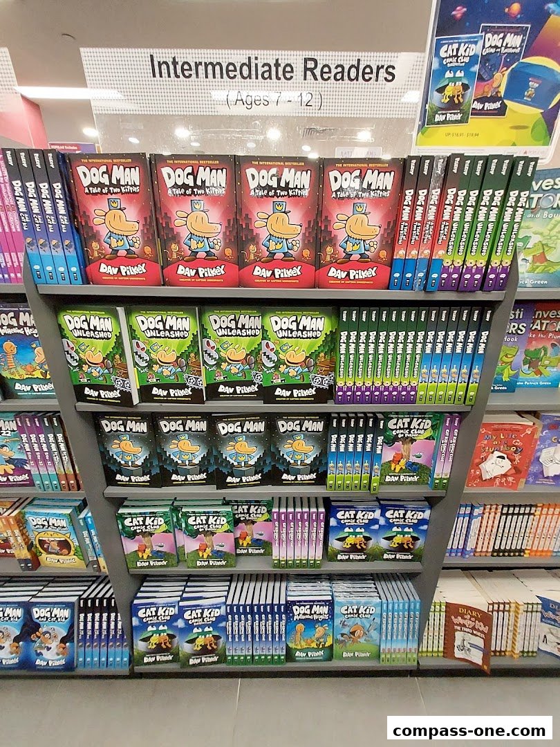 Shelves filled with children's books, primarily the 'Dog Man' and 'Cat Kid' series, categorized for intermediate readers.