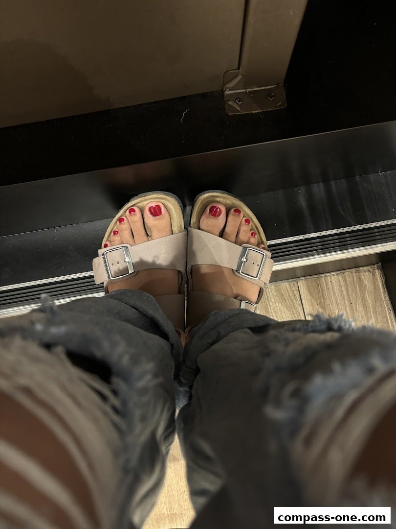 A person wearing taupe Birkenstock sandals with red nail polish on their toes.