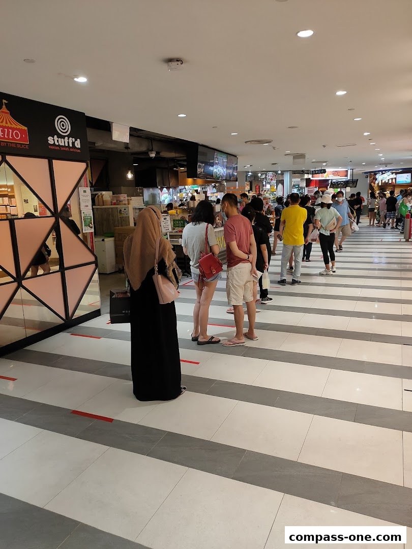 People queuing at food stalls in a mall, with a prominent sign for Crave Nasi Lemak.
