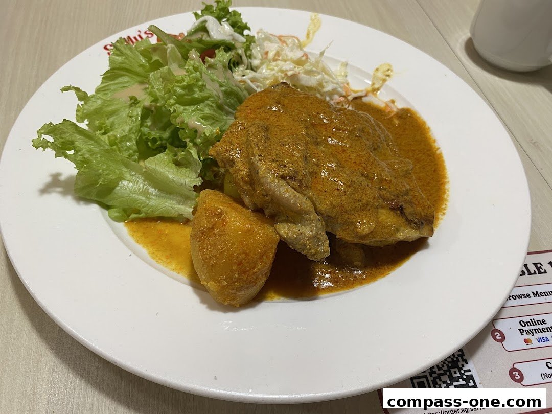 A plate of curry chicken with potatoes and a side salad from Sally's.