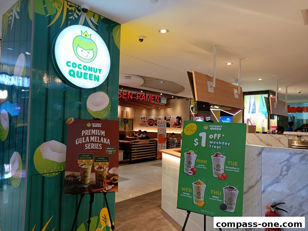 The Coconut Queen shop front with promotional posters for drinks and a sign.
