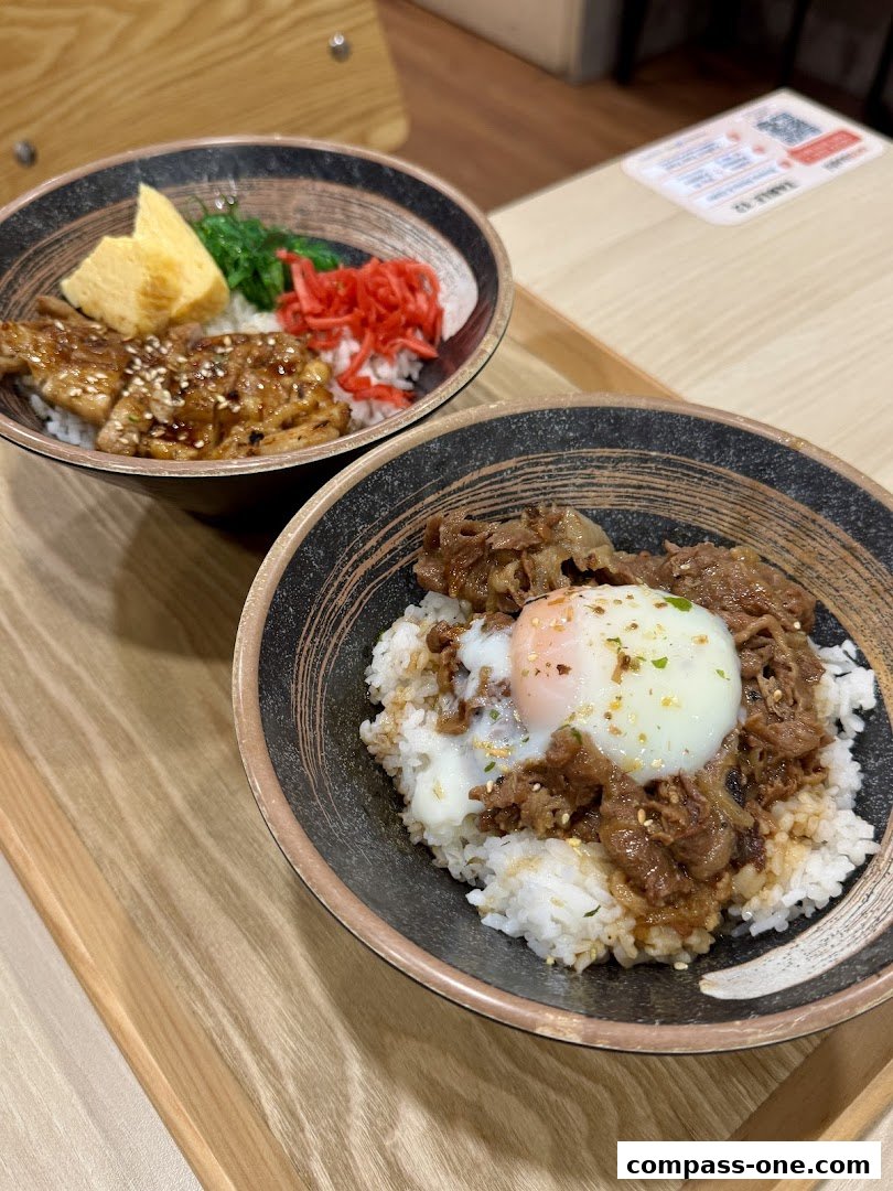 Two bowls of Japanese rice bowls with meat and egg on a wooden tray.