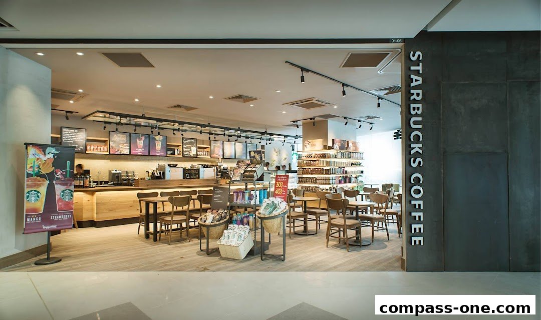 Interior view of a Starbucks coffee shop with seating, counter, and merchandise displays.