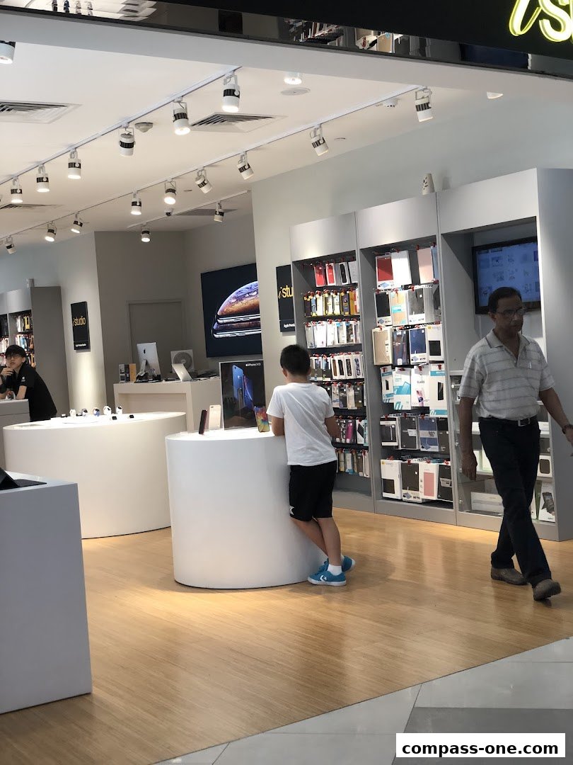 Interior of an iStudio store showcasing Apple products and accessories with customers browsing.