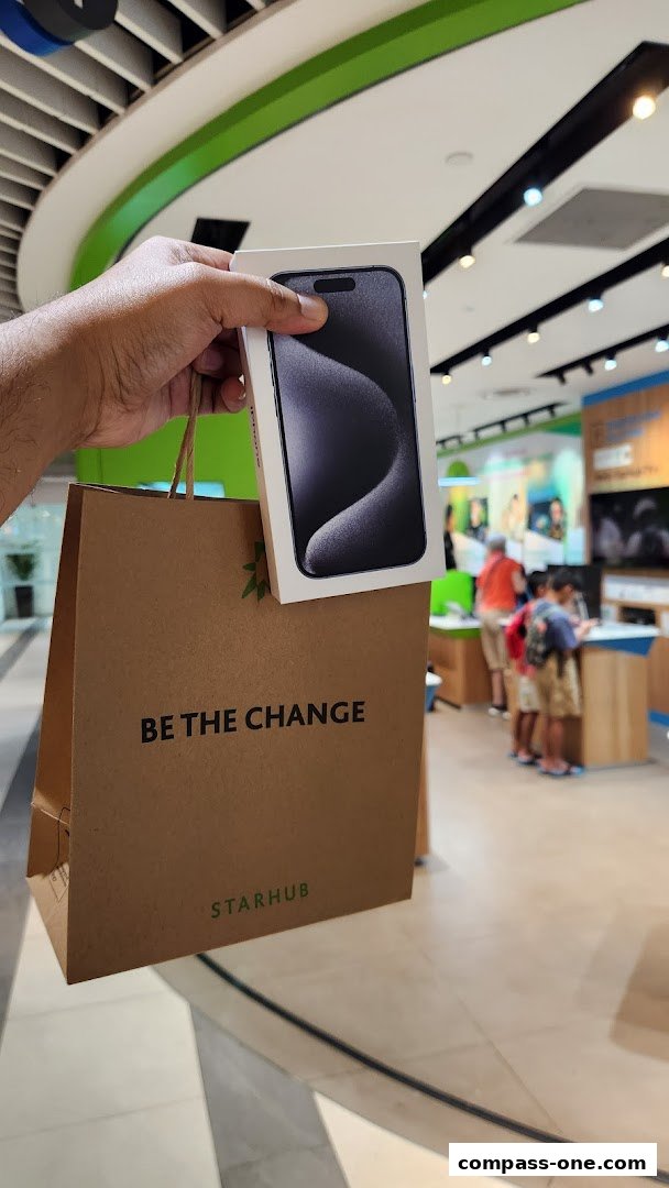 A hand holds a StarHub shopping bag with a new iPhone box.