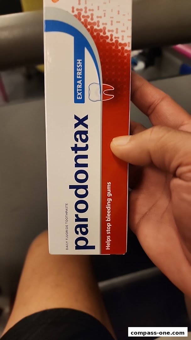 A hand holds a box of Parodontax toothpaste with 'Extra Fresh' and 'Helps stop bleeding gums' text.