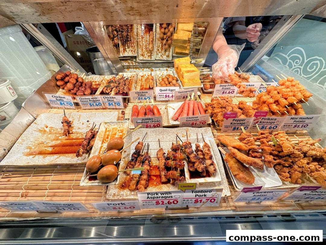A display of various Japanese skewers and fried items with price labels.