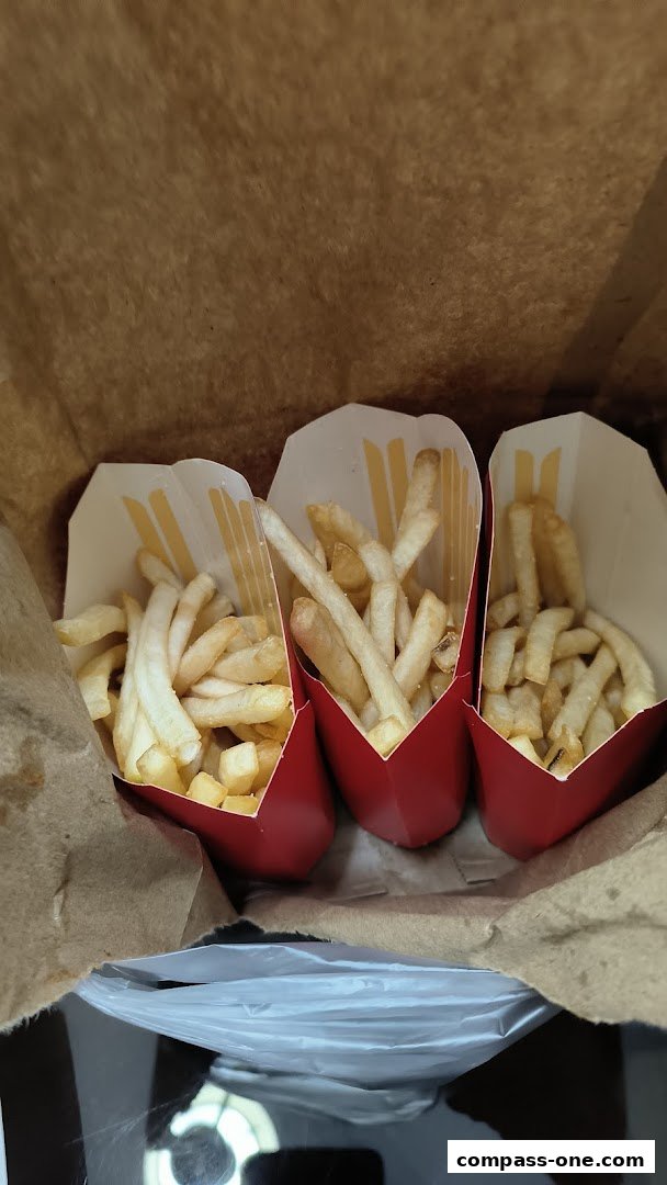 Three servings of McDonald's fries in red containers inside a brown paper bag.