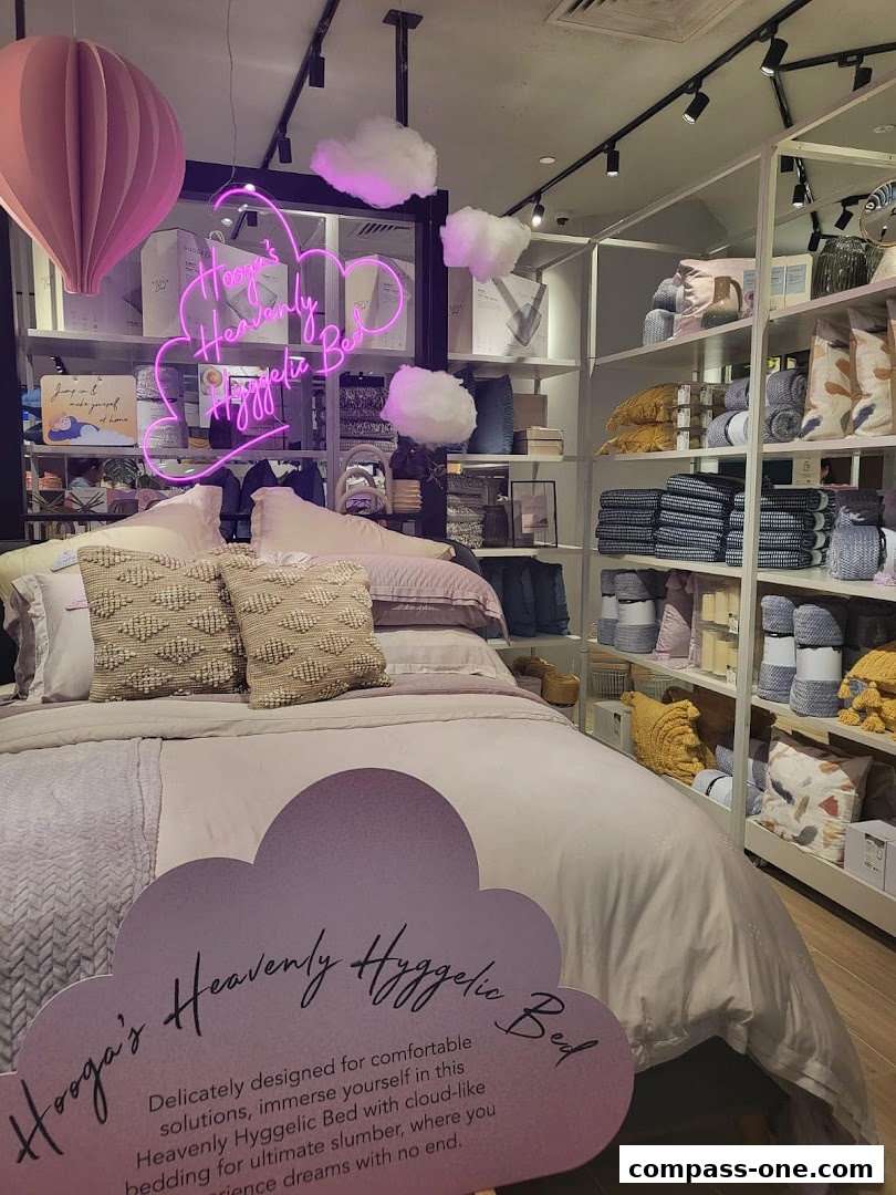 A beautifully made bed display with neon cloud decor and bedding products on shelves.