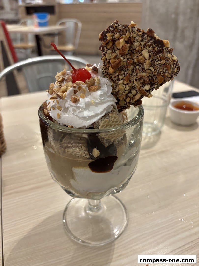 A delicious ice cream sundae with whipped cream, nuts, chocolate, and a cherry.