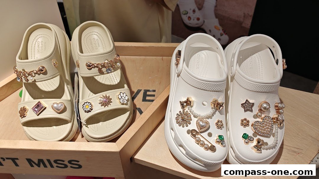 Two pairs of stylish Crocs sandals and clogs adorned with decorative charms and embellishments.