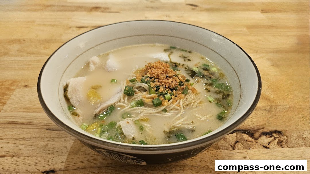 A close-up shot of a steaming bowl of noodle soup with fish slices and toppings.