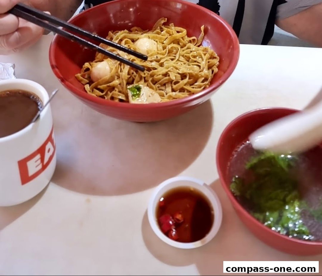 A close-up of a delicious noodle dish with a side of soup and dipping sauce.