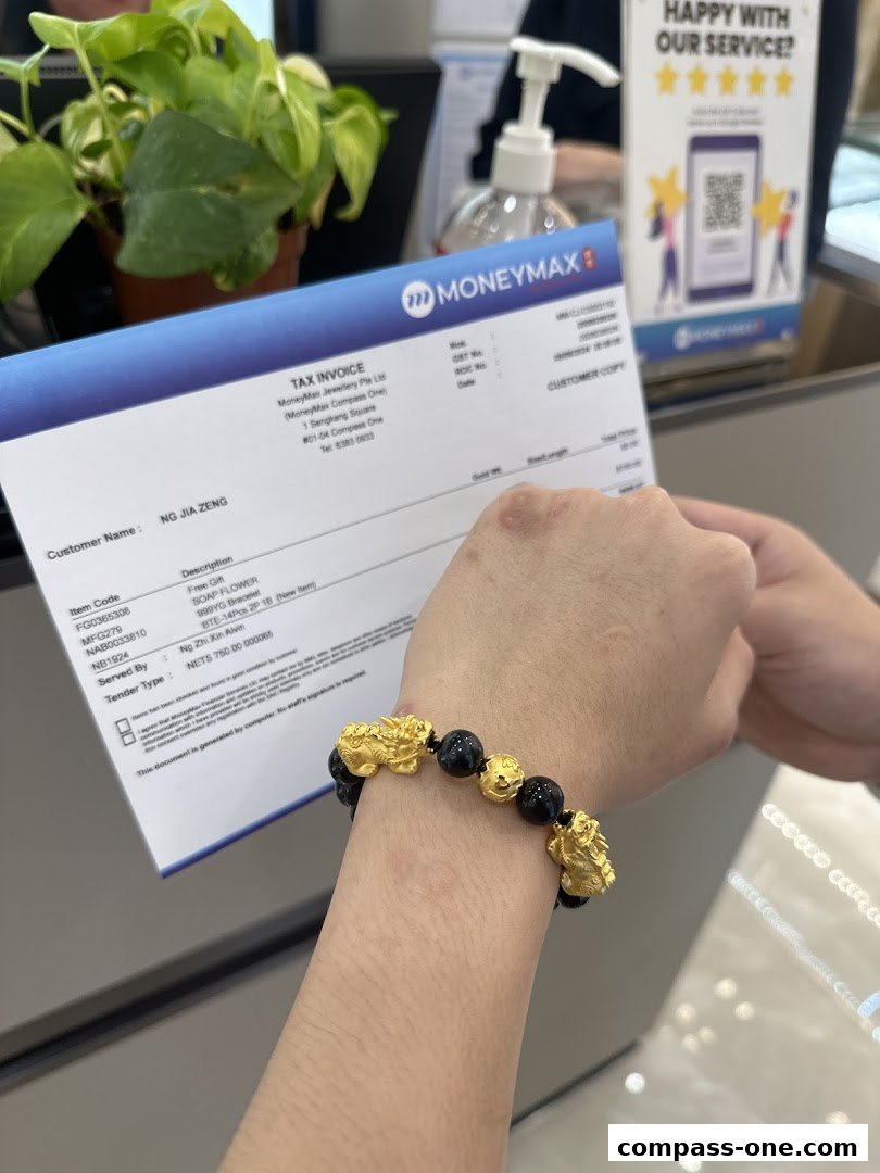 A customer holds a tax invoice and a gold bracelet with black beads.