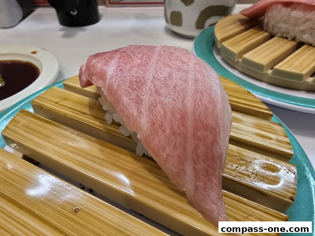 A close-up of a piece of fatty tuna sushi on a wooden plate with soy sauce in the background.
