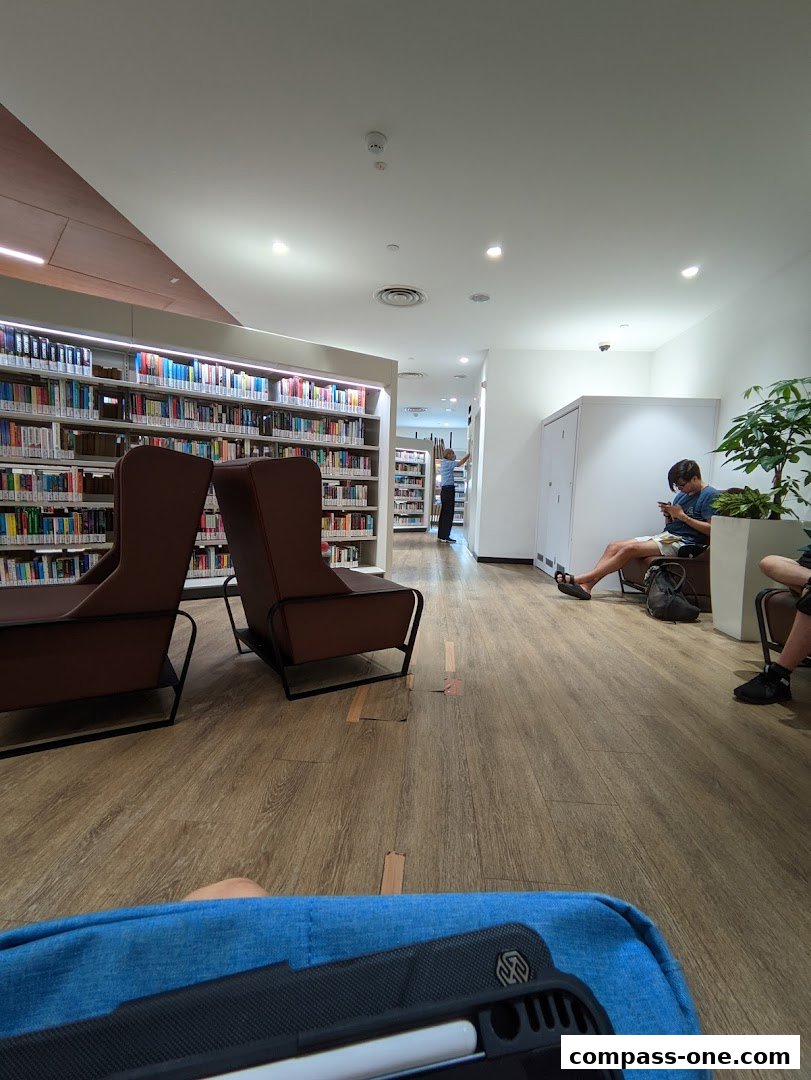 Interior of a library with bookshelves, seating areas, and people reading.