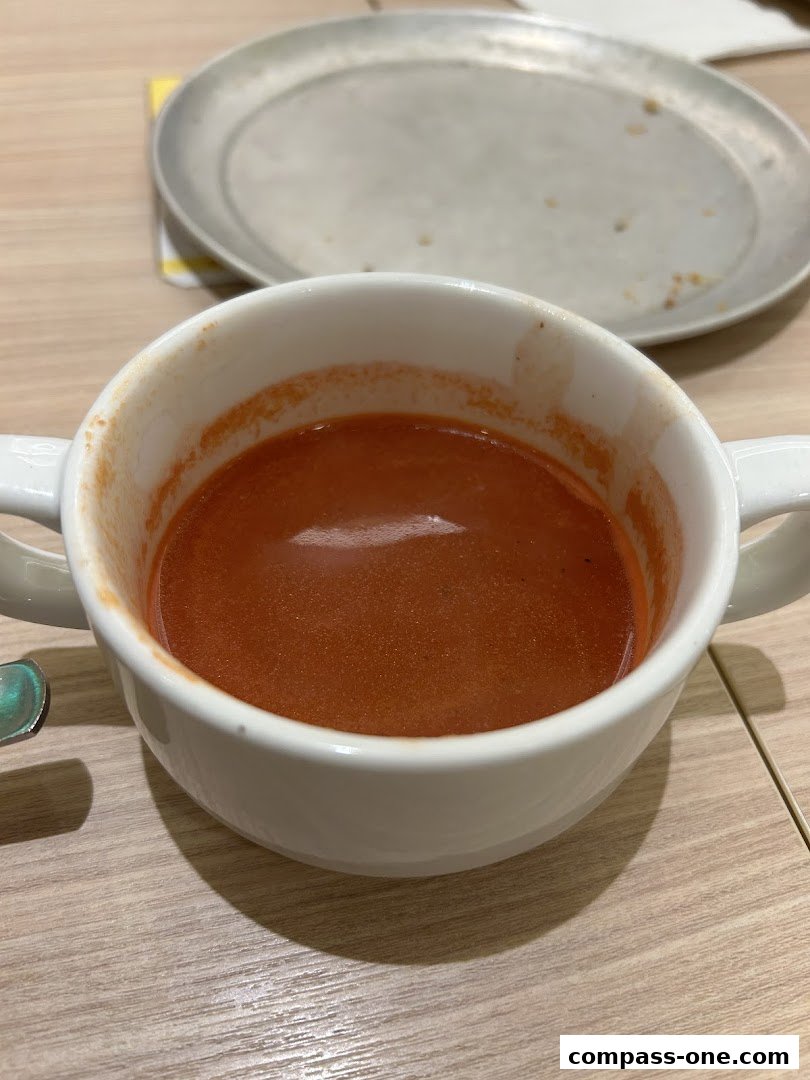 A close-up shot of a bowl of tomato soup with a metal plate in the background.