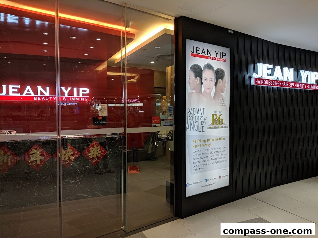 The exterior of a Jean Yip beauty salon with illuminated signage and a promotional poster.