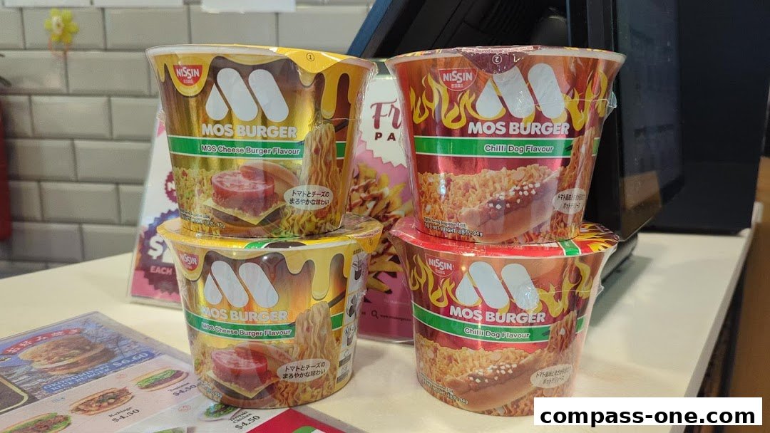 MOS Burger instant noodle cups in Cheese Burger and Chilli Dog flavors are stacked on a counter.