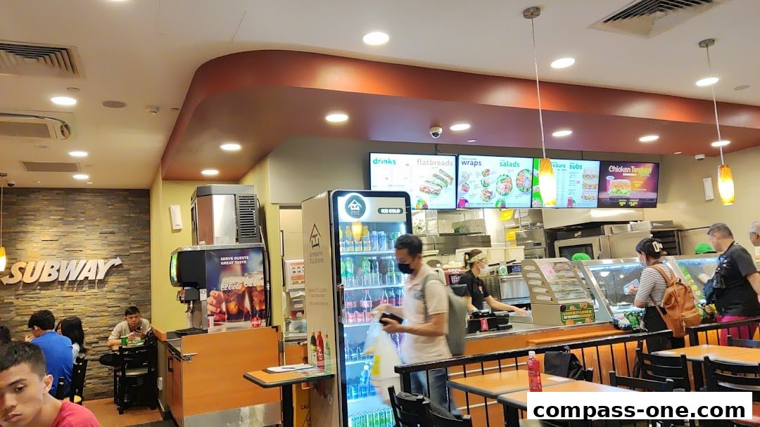 Interior view of a Subway restaurant with customers ordering and dining.