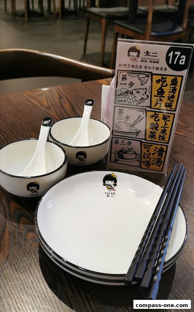 Table setting with plates, bowls, spoons, chopsticks, and a menu at Fu Qi Grilled Fish.