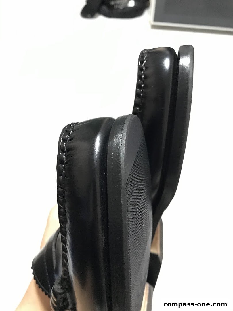 Close-up view of the sole and stitching on a pair of black leather shoes.