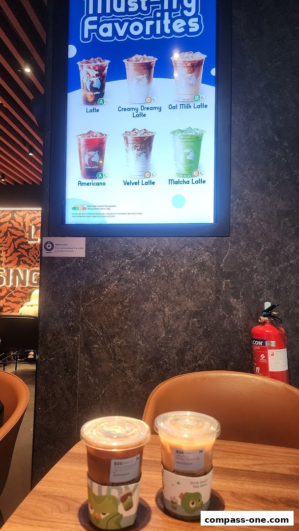 A menu board displays various coffee drinks, with two iced coffees on a table.