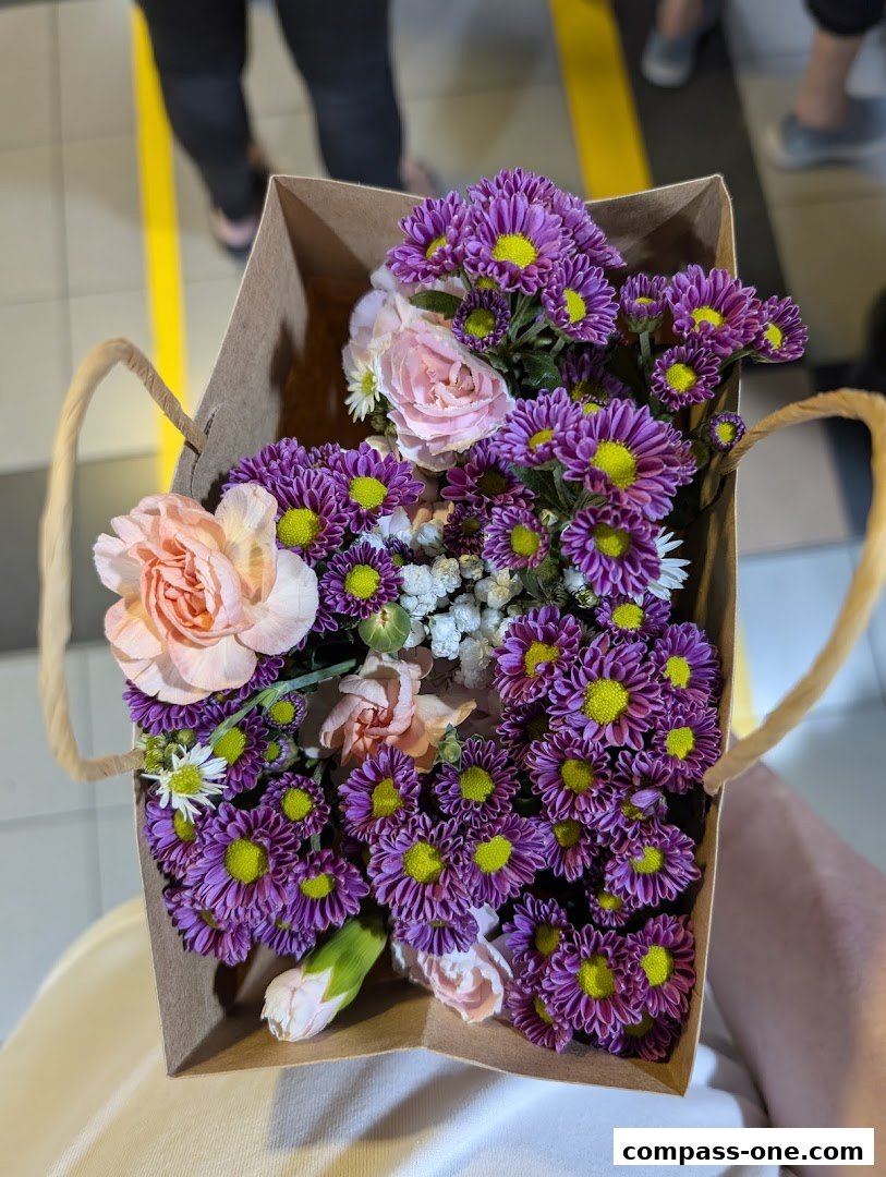 A paper bag filled with a vibrant bouquet of purple and pink flowers.