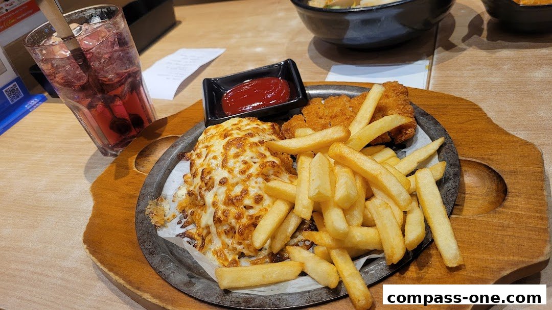 A plate of cheesy ramen with fries, chicken nuggets, and a drink.