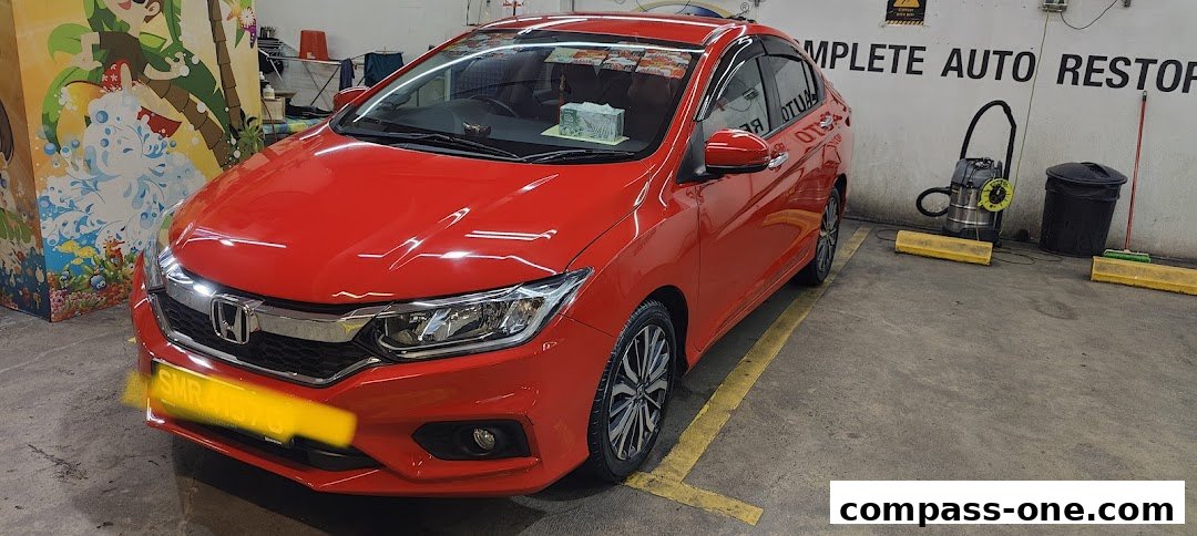 A shiny red car parked inside a garage with cleaning equipment in the background.